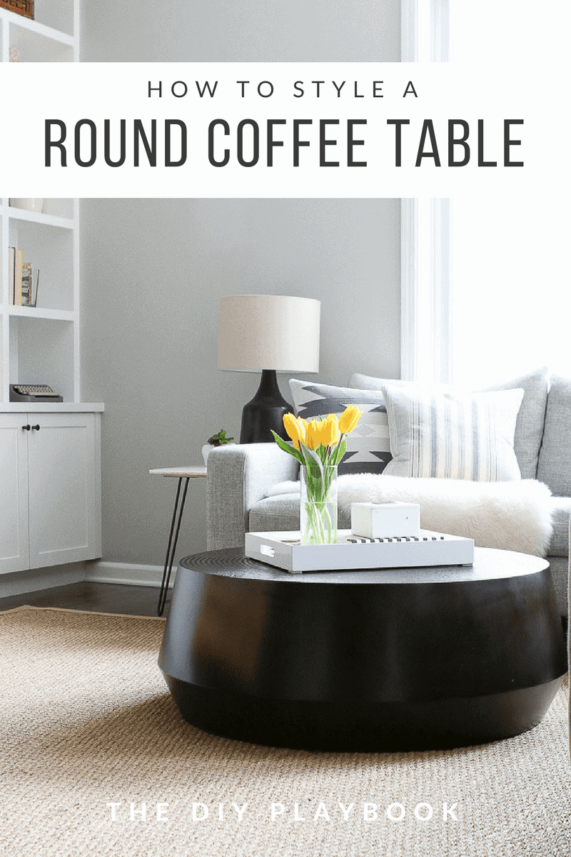 Styling a round coffee table can be tricky and there are many things to keep in mind. We always like to start with a tray, especially a rectangular tray if you have a round table. Then add coffee table books, decor items, and some storage for a finished look! #coffeetable #coffeetablestyling #coffeetabledecor #blackcoffeetable #livingroom